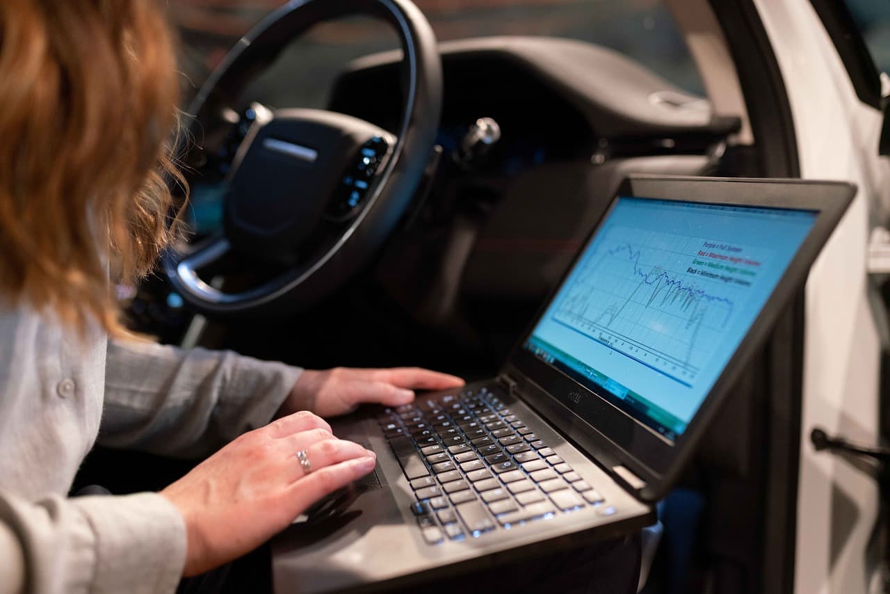 Technician running diagnostics on a laptop inside a car