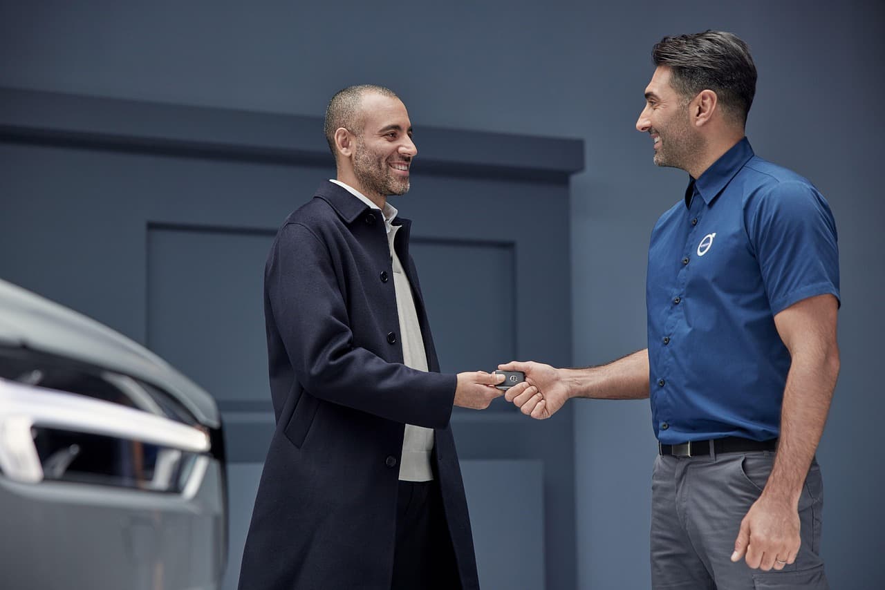 Customer and mechanic talking by a car